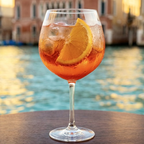 A glass of Aperol Spritz with ice and an orange slice.